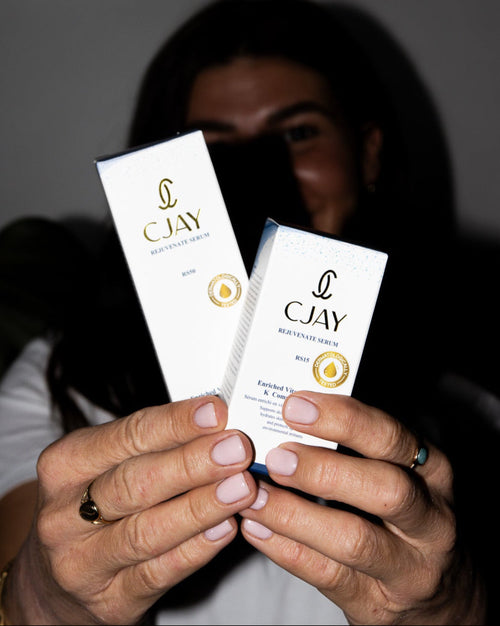 Person holding two CJAY beauty serum packets with a blurred background